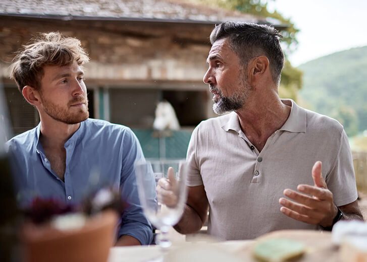 two men talking outside at a table