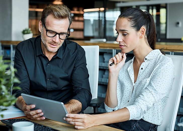 man showing woman information on tablet