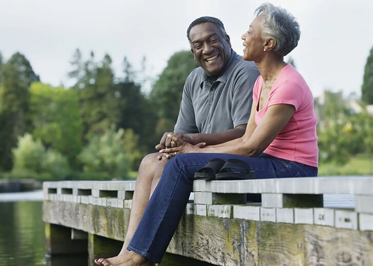 Older couple sitting on the dock smiling
